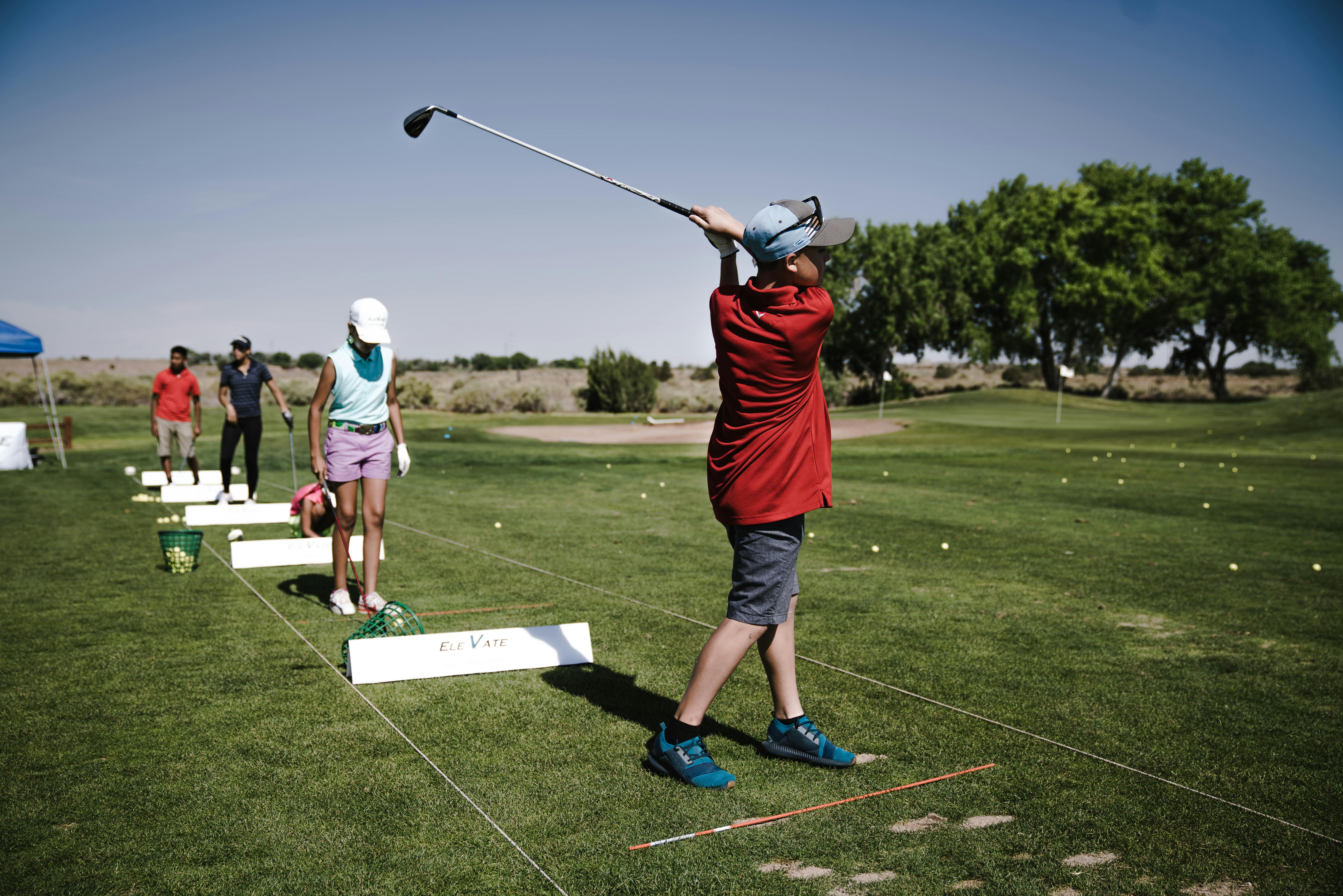 Des personnes pratiquent le golf sur un terrain d'entraînement en plein air.